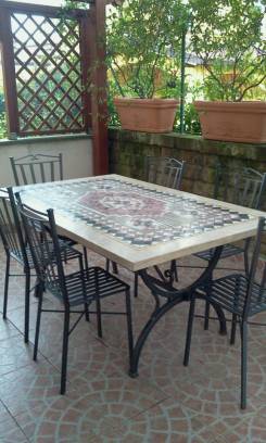 Tavolo con sedie in ferro con mosaico sotto  una veranda